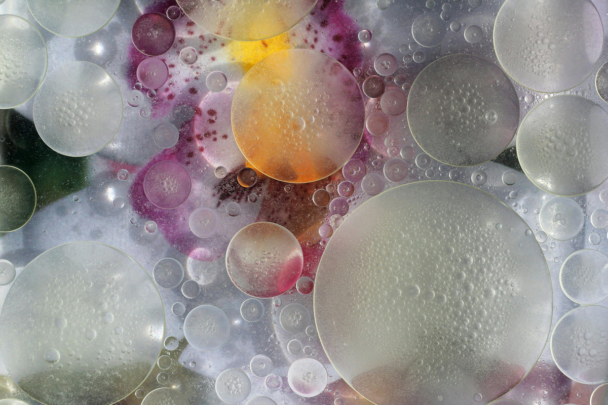 Macro of oil bubbles in pink and amber light, inked skin at a cellular level