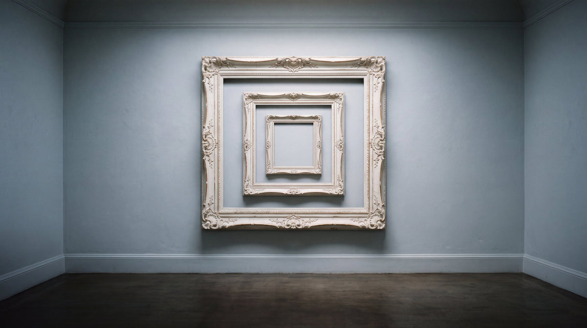 An ornate white picture frame on a pale gallery wall with a much smaller frame nested inside it, a thin teal line along the floor