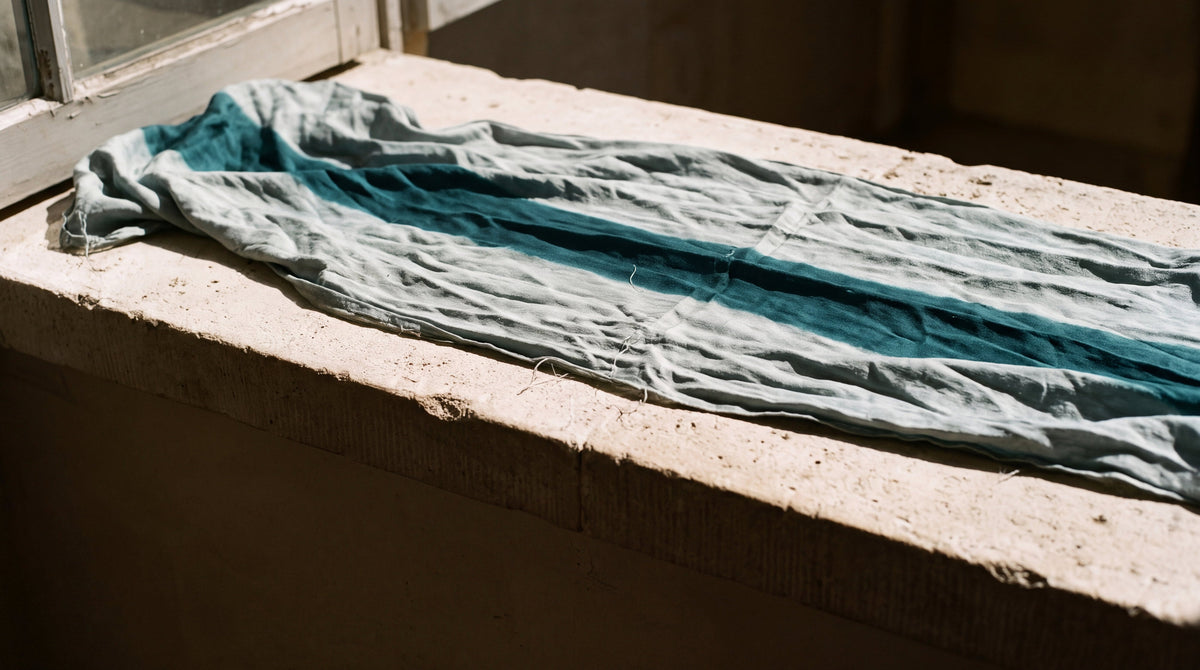 Teal silk bleached by the sun on a windowsill with one band of original colour, why tattoos fade