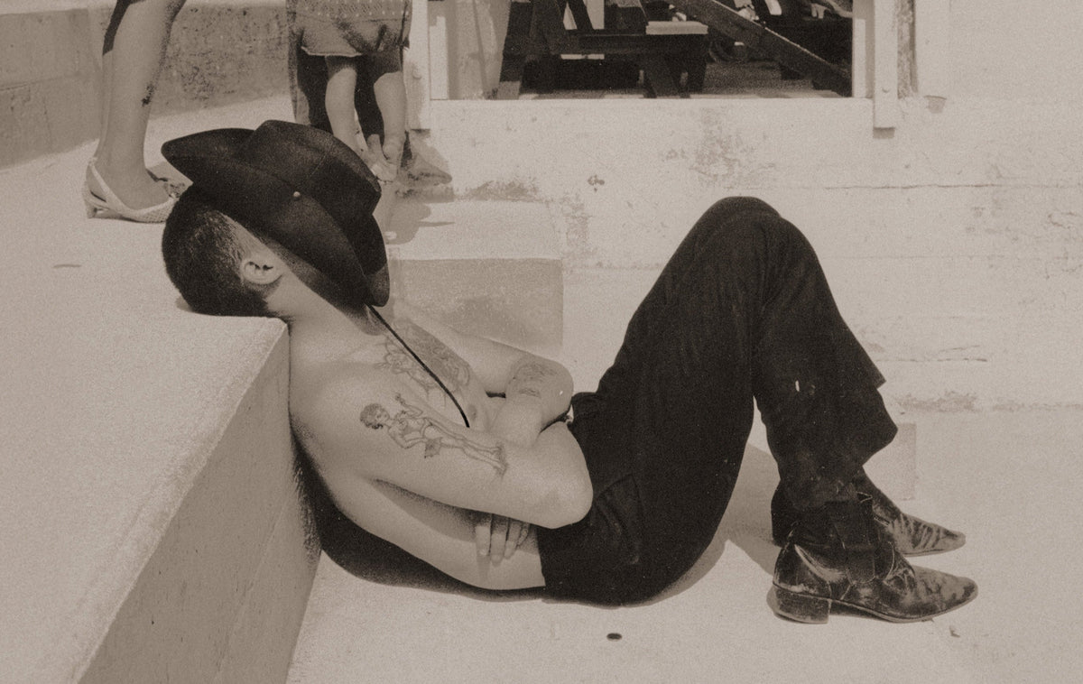 Vintage photograph of a tattooed man reclining, tattoo culture through the decades