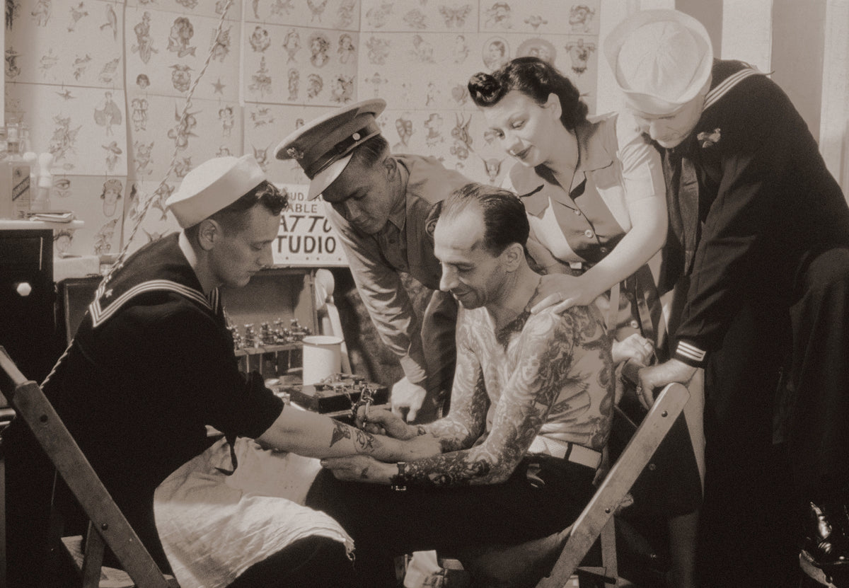 Vintage photograph of sailors gathered around a tattoo artist, milestones in tattoo history