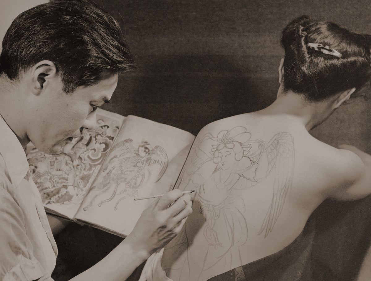 Vintage photograph of a tattoo artist working on a woman’s back, tattoo styles through history